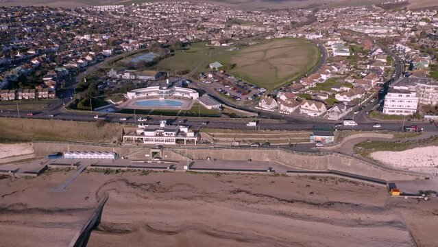 Aerial footage along Saltdean seafront in East Sussex with the Saltdean art deco designed Lido in view and the Whitecliffs Cafe between the white chalk cliffs.