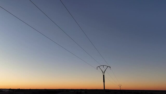 drone view in flight backwards of the detail of a power line and the sky at dawn