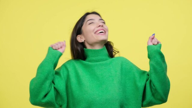 Jubilant Caucasian woman is captured in a moment of celebration, expressing joy and triumph. She filled with positivity and the elation of success on yellow background.