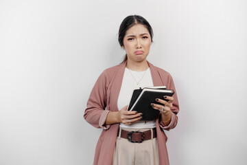 Fototapeta premium A sad young Asian woman wearing cardigan while holding books, isolated by white background.