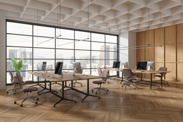 Corner view of office interior with chairs, pc computers on desk near window