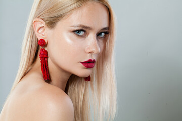 Elegant blonde woman with fashion jewelry eraring, blond hairstyle, clean fresh skin and red...