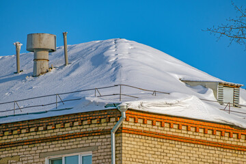 A fragment of the snow-covered roof of an apartment building on a winter day