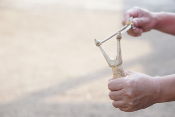 Close up hands hold wooden slingshot for playing shooting game outdoor. Concept ,Thai traditional...