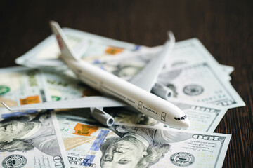 Airplane and money. Plane on the background of USA dollars. The cost of travel, air tickets and flights, financial expenses for vacation.