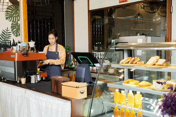 Fototapeta premium Closeup Asian young small business owner female service customers ordering in cafe coffee shop restaurant, barista waitress worker working bakery shop, single woman start-up business entrepreneur
