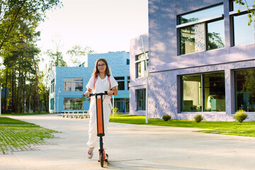 Pretty young smiling girl student riding blue electric kick scooter