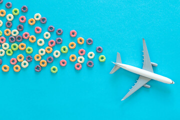 Colorful fruit corn rings and toy airplane on a blue background. Children breakfast option with...