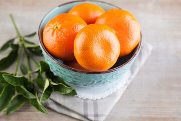 Fruit clementine or tangerine with green leaves in blue plate