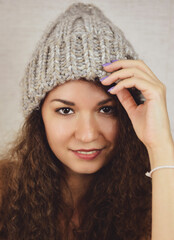 Portrait of a beautiful girl in a knitted gray hat in close-up. Girl with curly hair.