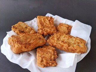 Fried tempeh served on a plate on a black background