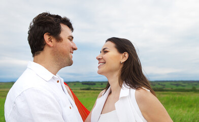 Fototapeta premium Young happy couple in love with red fabric in summer day