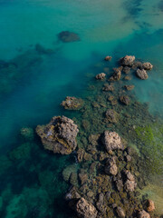 Fototapeta na wymiar Sharp rocks formation in turquoise sea in Malta aerial top down. Vertical background photo. Natural sea colors palette in Mediterranean paradise.