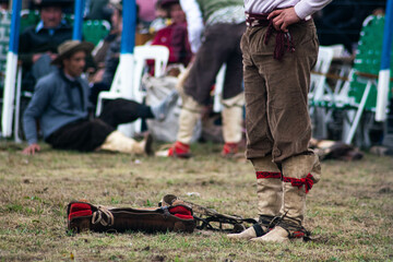 gaucho argentino con sus botas de cuero parado en un campo de domas tradicional - obrazy, fototapety, plakaty