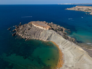 View point with flat rock and golden Qarraba Bay beach. Summer in Malta high altitude aerial. View...