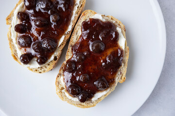 Whole grain bread with strawberry jam on top. Composition with delicious homemade jam on a plate. Breakfast and snack concept.