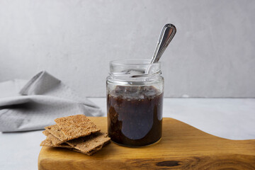 Strawberry jam in a glass jar on a light gray background with sliced ​​bread. Composition with...