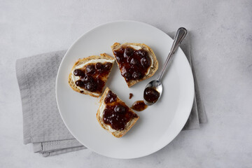 Whole grain bread with strawberry jam on top. Composition with delicious homemade jam on a plate. Breakfast and snack concept.