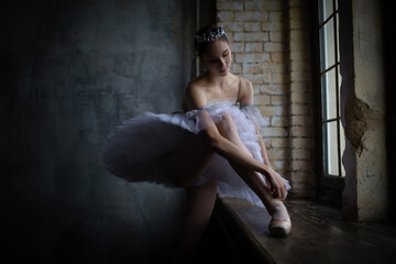 Ballerina adjusts her pointe shoes.
