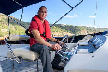 Young caucasian man steering motor yacht. Motor boat captain. Master of yacht. Yachting concept....