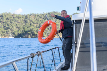 Young caucasian man with life buoy. Motor boat captain. Man over board. Yachting concept. Man...