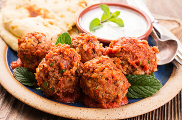 Traditional Persian slow cooked koofteh nokhod-chi meatballs with yoghurt and flatbread served as close-up on a design plate - obrazy, fototapety, plakaty