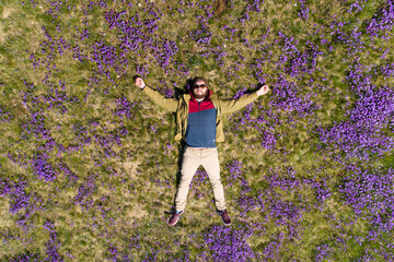 bearded man lies on the field in violets top-down view