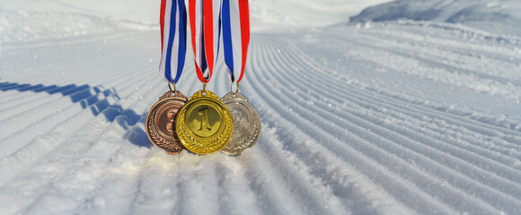 real Gold, silver and bronze medals hanging on red ribbons isolated lying on prepared, new snow ski...