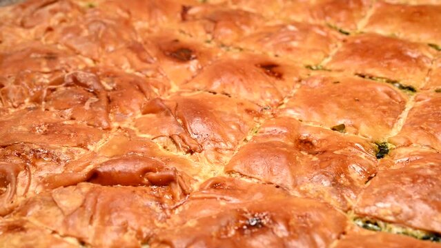 freshly baked spanakopita (spinach pie) in tray rotating