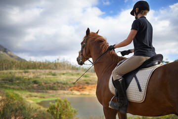 Obraz premium Equestrian, horse and woman riding in nature on adventure and journey in countryside. Ranch, animal and rider outdoor with hobby, sport or walking a pet on farm with girl in summer at river in woods