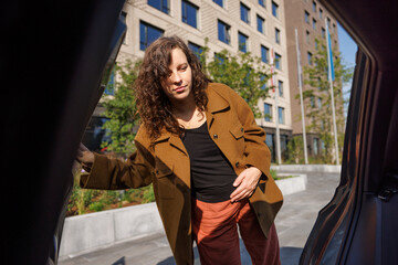 A pregnant woman gracefully enters her car, seamlessly incorporating a taxi service into her urban lifestyle for daily commuting, reflecting the nuances of contemporary city living