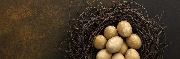 Cosmic Easter eggs in a nest on a brown background, top view, copy space, Easter banner
