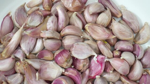 A mesmerizing macro view of garlic cloves, showcasing intricate textures and vibrant colors. Witness the natural beauty of garlic up close. Food stock footage. 4K.
