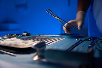 Close up of partial doctor hand taking scalpel from table