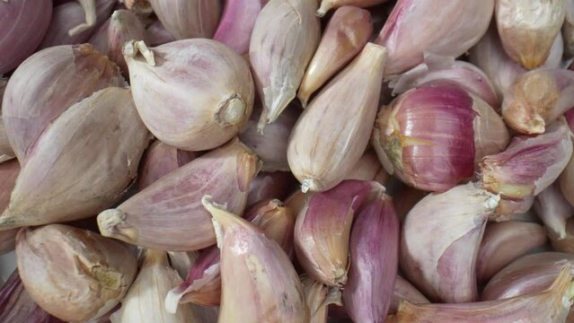 Marvel at the intricate textures of garlic cloves in this mesmerizing macro video. Every detail, from papery skin to pungent aroma. Food stock footage.
