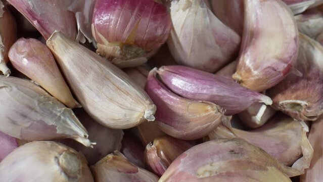 This macro video showcases the intricate textures and vibrant colors of garlic cloves up close, revealing their unique patterns and natural beauty. Food stock footage.
