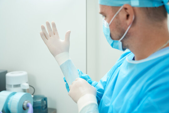 Partial image of male doctor put on latex glove on hand before surgery