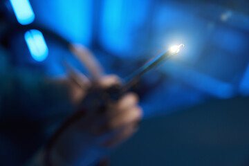 Selective focus of lighting hysteroscope in hands of blurred male doctor