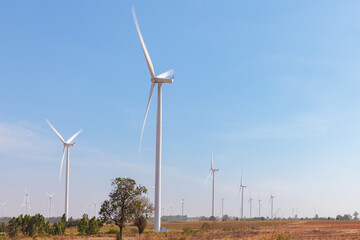 Field of wind turbines with motion blur on their blade using long exposure during sunny day and blue sky