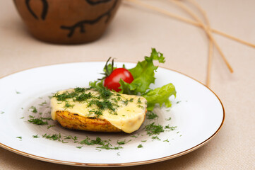 Baked potatoes with cheese and herbs on a plate