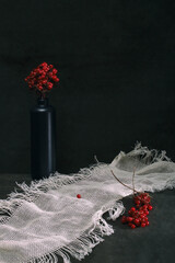 Still life with red viburnum in a vase and white cloth