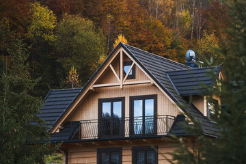 A cozy home nestled at the forest’s edge with a detailed wooden window accentuating its architectural beauty.