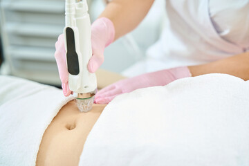 Cropped of female cosmetologist doing microneedle rf lifting of woman belly skin