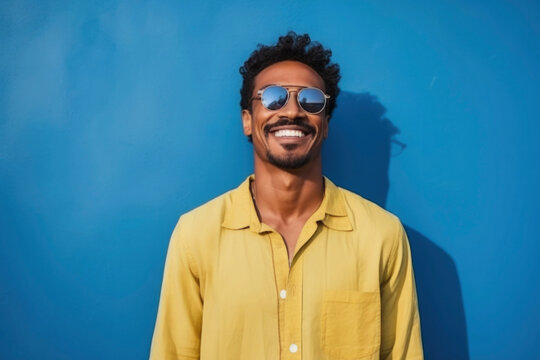happy Moroccan man with typical moroccan tunic standing against blue wall