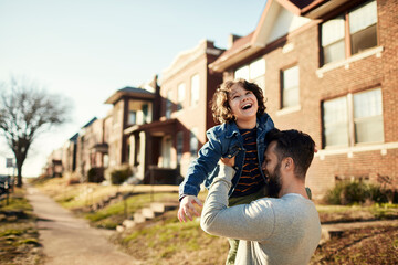 Happy child playing with father in sunny suburban street