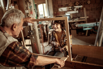 Obraz na płótnie Canvas Grandfather and grandson enjoying carpentry work in a home workshop