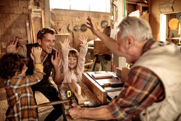 Obraz na płótnie Canvas Happy family woodworking together in a workshop