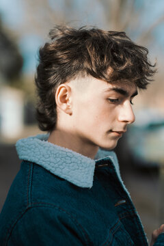De perfil chico apuesto luciendo corte de cabello mullet