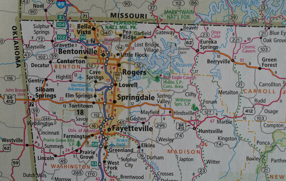Close up view of a map of northwest Arkansas on a road atlas. The area includes Fayetteville, Springdale, and Bentonville, the headquarters of Walmart.