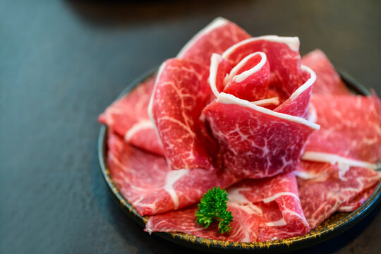 Sliced wagyu marbled beef for yakiniku on plate on black background,